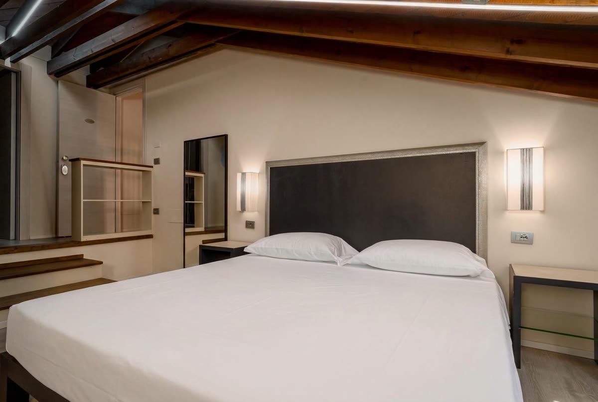 Ai Cannoni — il letto matrimoniale e i gradini in legno che salgono a sinistra