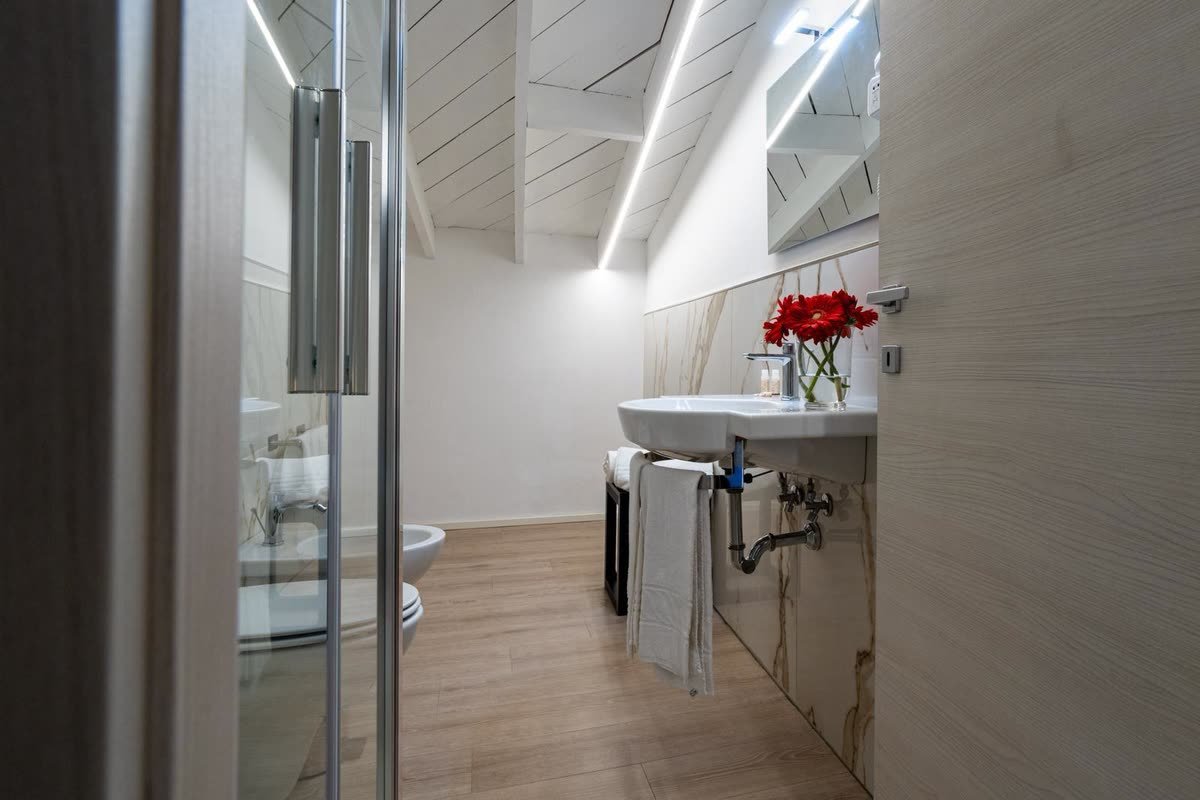 Ai Cannoni — il bagno privato visto dalla porta, lavabo con fiori freschi