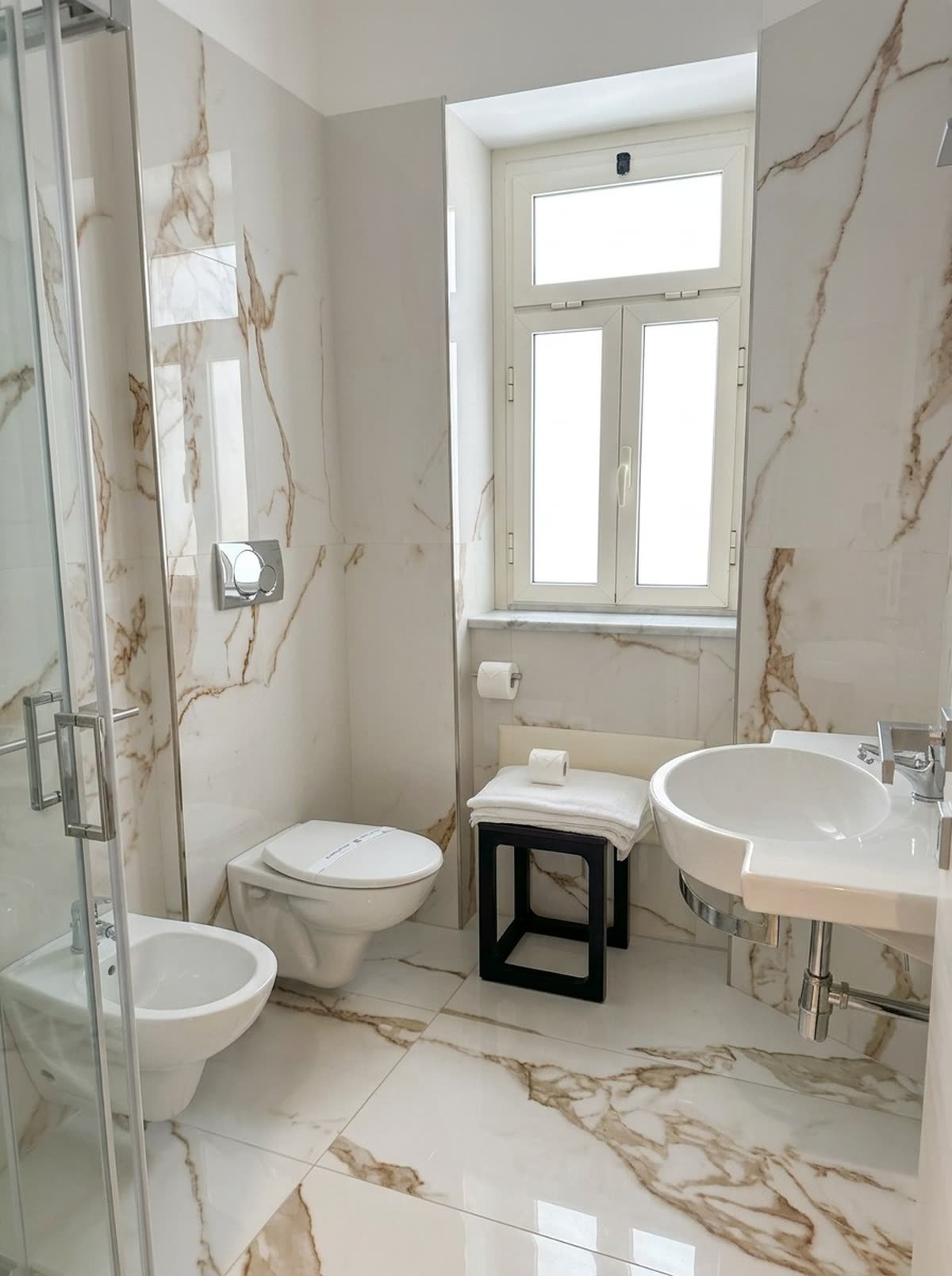 Ai Faraglioni — il bagno in marmo con doccia e finestra